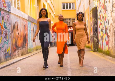 San Sebastian, Gipuzkoa Spagna, febbraio 2021: Stile urbano alla moda con tre ragazze nere africane in una strada cittadina. Passeggia e guarda Foto Stock