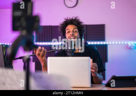 Semplifica la registrazione di un podcast utilizzando il microfono e il laptop seduti in studio Foto Stock