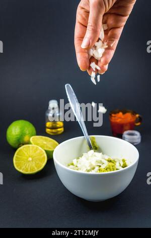 Iniziamo con la cipolla e mescoliamo con un cucchiaio l'avocado tritato. Ricetta per preparare un bel guacamole Foto Stock