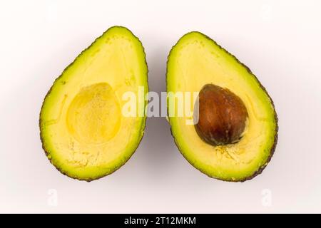 Mani di una donna che separa l'avocado in due. Ricetta per preparare un bel guacamole Foto Stock