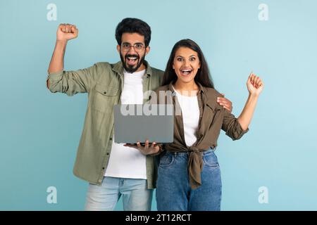 Emotiva felice bella coppia indiana che utilizza il laptop, gesturing Foto Stock