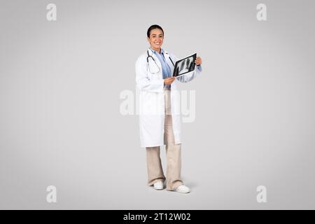 Medico donna che tiene in braccio e analizza i raggi X polmonari, per tutta la lunghezza Foto Stock