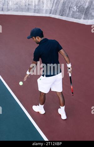 Lunghezza completa di un tennista maschile con palla e racchetta alla linea di base Foto Stock