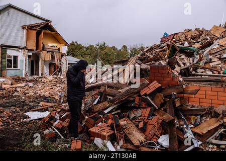 Un uomo triste in una casa in rovina. Senza speranza, senzatetto, risultato di conflitti militari e calamità naturali concetto. Foto Stock