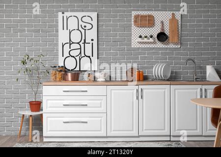 Lavandino, piano portapiastre e utensili su banchi bianchi in una cucina moderna Foto Stock