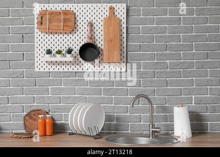 Lavandino, piano portapiastre e utensili su banchi bianchi in una cucina moderna Foto Stock