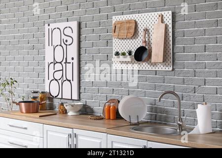 Lavandino, piano portapiastre e utensili su banchi bianchi in una cucina moderna Foto Stock