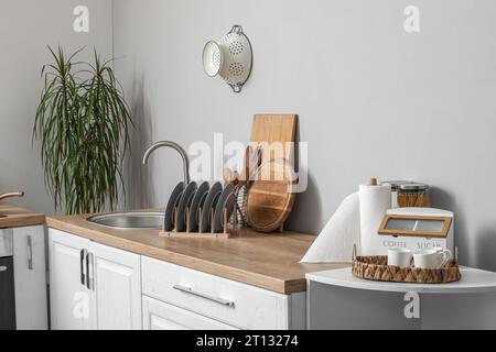 Banchi da cucina bianchi con tagliere, portapiastre, lavandino e utensili Foto Stock