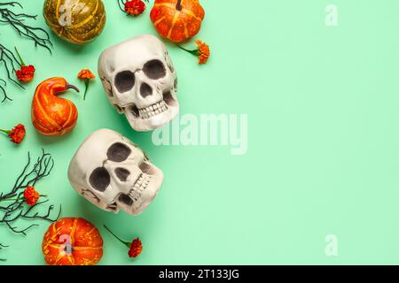 Teschi umani con fiori di calendula, zucche e rami d'albero su sfondo verde Foto Stock