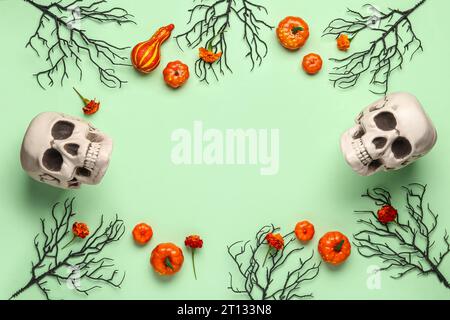 Cornice composta da teschi umani, fiori di calendula, zucche e rami d'albero su sfondo verde Foto Stock