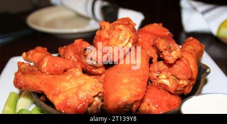 Ali di bufalo in una piccola padella in ghisa su un piatto in un ristorante da vicino Foto Stock