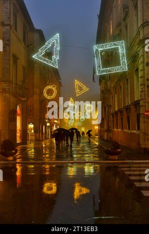 Le luci natalizie e la loro immagine speculare su corso Pietro Vannucci da Piazza Italia. Girato in una serata piovosa a Perugia, in Italia Foto Stock