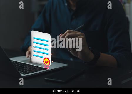 Un uomo d'affari utilizza l'elenco di controllo del notebook valutazione della soddisfazione dei clienti su un servizio di documenti digitali controllo della qualità, certificazione documento schermo virtuale. Foto Stock