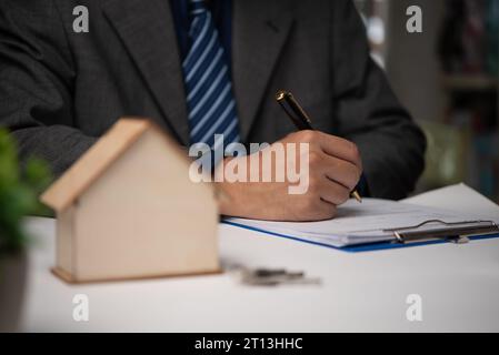 Uomo d'affari che firma un contratto per l'acquisto di una casa o di un agente immobiliare. Investimenti e prestiti bancari o assicurazione per la casa. Foto Stock