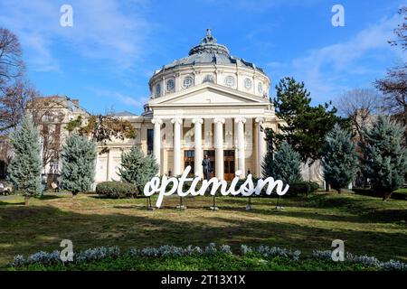 Bucarest, Romania, 2 gennaio 2022: Parola ottimista visualizzata di fronte al rumeno Atheneum Ateneul romano), edificio circolare che è la conce principale Foto Stock