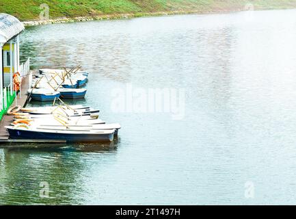 Due barche con remi all'ormeggio. Barche sul molo con un salvagente. Passeggia in barca lungo il fiume. Foto Stock