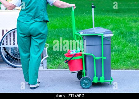 Il custode sta funzionando. L'inserviente con gli articoli per la pulizia. operaio sanitario spazzatura strada Foto Stock