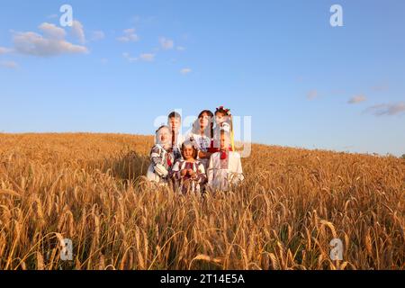 Famiglia di sei persone in camicie ricamate su un campo di grano. Ragazzi e ragazze sono una felice famiglia Ucraina.giorno dell'indipendenza dell'Ucraina, Costituzione, em Foto Stock