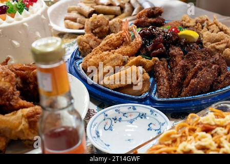 Cibi da festa in tavola con pollo fritto, spaghetti, involtini primavera e salsa al peperoncino. Foto Stock