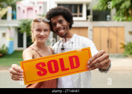 Ha venduto cartelloni in mano a una coppia felice e diversificata che ha comprato una nuova casa Foto Stock