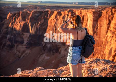 La ragazza ammira la vista dall'attrazione turistica Horseshoe Bend in Arizona. Foto Stock