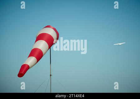 Windsock soffiato dal vento con un piccolo aeroplano sullo sfondo Foto Stock