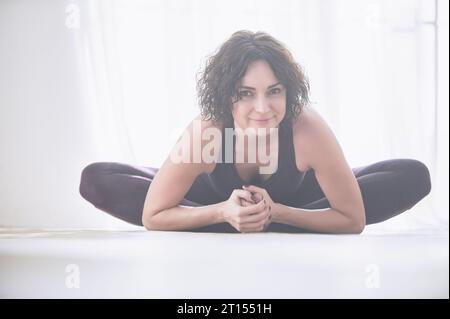 Bella giovane donna le pratiche yoga asana Baddha Konasana - angolo legato pongono in luce studio yoga. Foto Stock