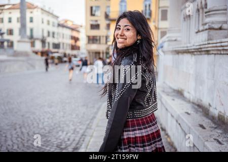 Una ragazza ispanica sorridente mentre cammina per le strade della città Foto Stock