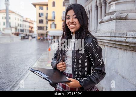 Una giovane studentessa sorridente di vitiligine ha in mano una cartella Foto Stock