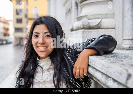 Una ragazza adolescente con vitiligine si appoggia contro il muro della città Foto Stock