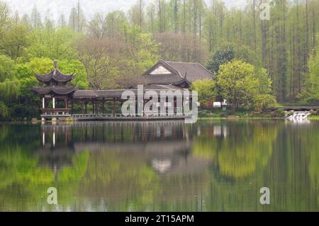 Ponte tradizionale cinese con padiglione sulla costa del Lago Ovest, parco pubblico nella città di Hangzhou, Cina. Foto Stock