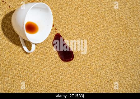 Caffè versato su un divano giallo, tappeto o tappezzeria. Rivestimento in tessuto rovinato. Concetto di pulizia e rimozione delle macchie Foto Stock