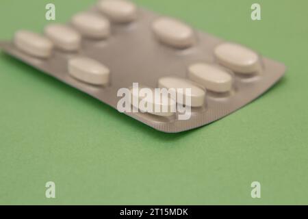 Goiânia, Goias, Brasile – 10 ottobre 2023: Un blister di plastica e alluminio con compresse su una superficie verde. Foto Stock