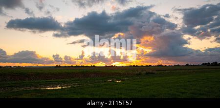 Vista panoramica delle nuvole color oro con contorni argentati durante un tramonto sulla campagna olandese. Foto Stock