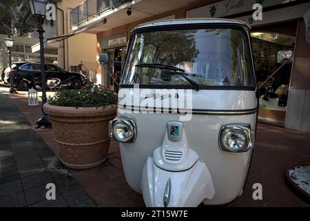 Bianco Piaggio Ape Calessino sul marciapiede accanto alle vetrine di una cittadina italiana sul mare Foto Stock