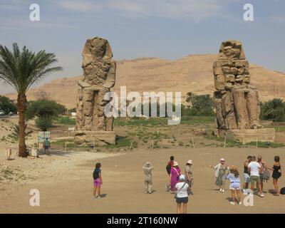 In piedi di guardia al tempio memoriale di Amenofi dal 1350 a.C., i giganteschi Colossi gemelli di Memnon sono alti 18 m (60 piedi) e un'attrazione turistica di Luxor. Foto Stock