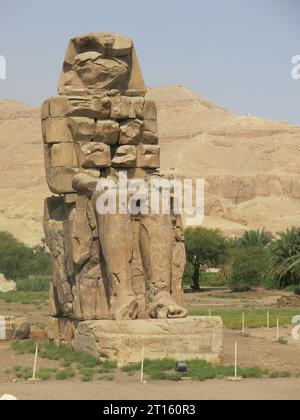 In piedi di guardia al tempio memoriale di Amenofi dal 1350 a.C., i giganteschi Colossi gemelli di Memnon sono alti 18 m (60 piedi) e un'attrazione turistica di Luxor. Foto Stock