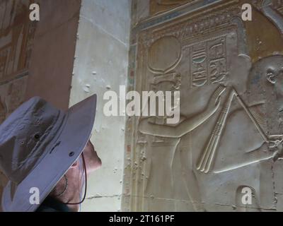 Un turista inglese maschio in un ampio cappello guarda le sculture sulle pareti del grande Tempio di Seti i ad Abido, necropoli storica dell'antico Egitto. Foto Stock