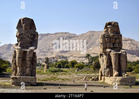 Luxor, Egitto - 8 ottobre 2021: I Colossi di Memnone, due enormi statue in pietra del faraone Amenofi III di fronte al suo tempio funerario, in corso di realizzazione Foto Stock