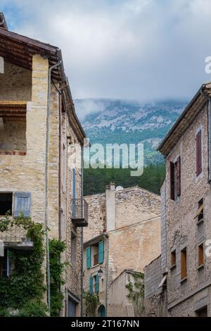 Facciate della strada e della Casa medievale nel villaggio di Chatillon en Diois con la montagna nascosta dietro le nuvole sullo sfondo. Foto Stock