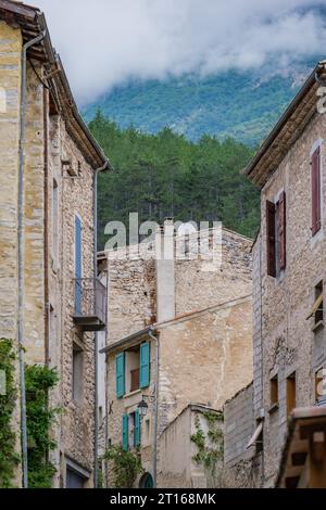 Facciate della strada e della Casa medievale nel villaggio di Chatillon en Diois con la montagna nascosta dietro le nuvole sullo sfondo. Foto Stock