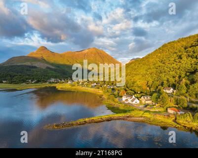 Vista aerea del lago d'acqua dolce loch Leven con l'ex Pier House nel villaggio di Glen Coe, sopra di esso il Pap of Glencoe, Highlands, alto 742 metri Foto Stock