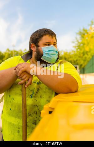 Lavoratore in una fabbrica di riciclaggio o in un punto pulito e spazzatura con una maschera facciale e con protezioni di sicurezza, nuovo normale, pandemia di coronavirus, covid-19. Foto Stock