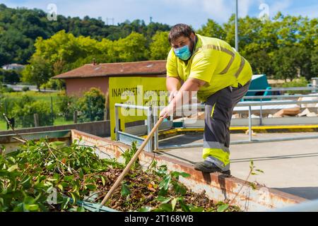 Lavoratore in una fabbrica di riciclaggio o in un punto pulito e spazzatura con una maschera facciale e con protezioni di sicurezza, nuovo normale, pandemia di coronavirus, covid-19. Foto Stock