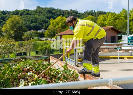 Lavoratore in una fabbrica di riciclaggio o in un punto pulito e spazzatura con una maschera facciale e con protezioni di sicurezza, nuovo normale, pandemia di coronavirus, covid-19. Foto Stock