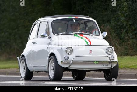 Bicester, Oxon., UK - 8 ottobre 2023: 1966 auto d'epoca Fiat 500 bianca che guida su una strada di campagna inglese. Foto Stock