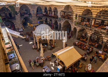 DIYARBAKIR, TURCHIA, 5 OTTOBRE 2023: Veduta di Hasanpasa Khan, edificio storico medievale dove la gente fa colazione e piccoli negozi, il centro Foto Stock