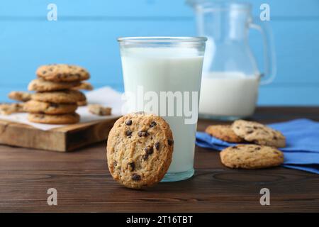 Deliziosi biscotti con gocce di cioccolato e un bicchiere di latte su un tavolo di legno Foto Stock