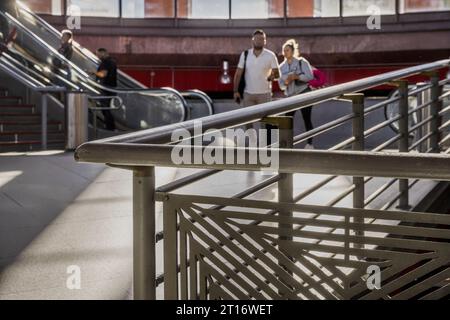 Accesso tra ringhiere e persone alle stazioni della metropolitana e dei treni dalle scale mobili Foto Stock