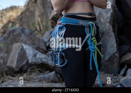 Primo piano di un'imbracatura da arrampicata con attrezzatura fissata alla base di una montagna, preparandosi a salire. Foto Stock